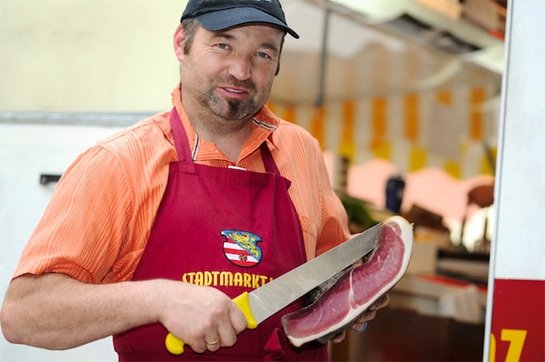 Peter Vergeiner mit Schürze und frisch aufgeschnittenem Speck am Lienzer Stadtmarkt